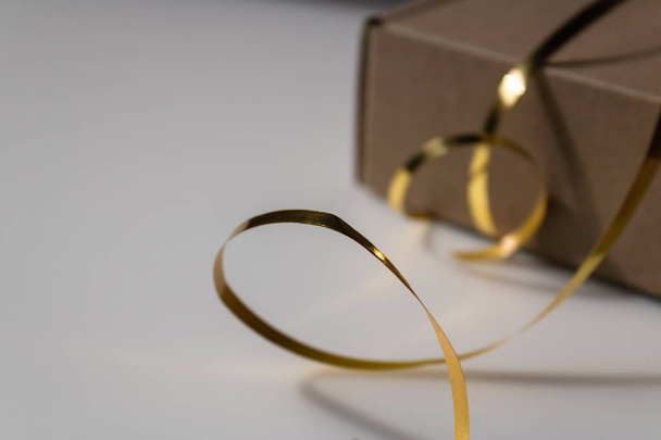 Golden foil ribbon with the closed cupboard gift box on the background - Image - Photo, Image