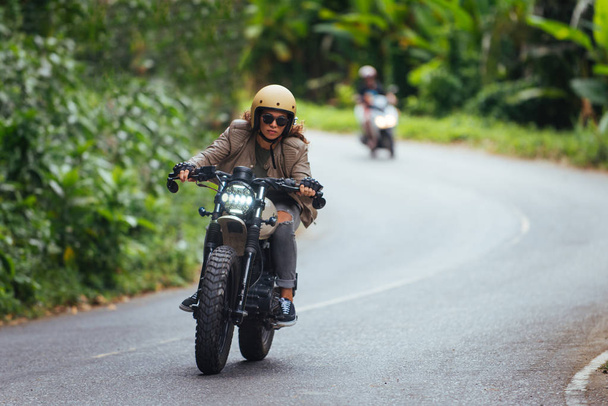 Female biker driving a cafe' racer motorbike - Photo, Image