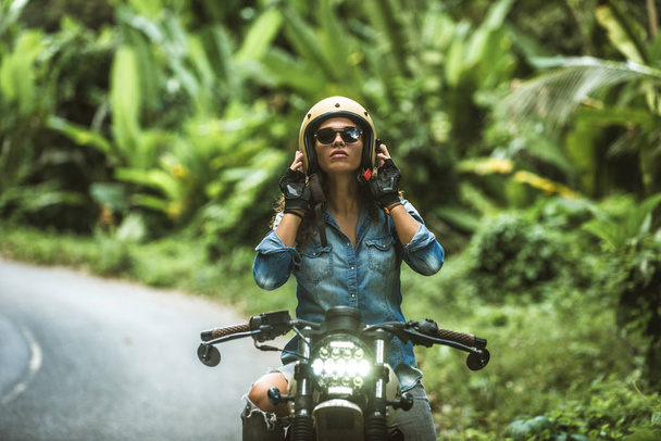 カフェのレーサーバイクを運転する女性バイカー - 写真・画像