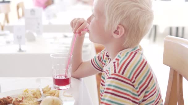 Красивий альбіносів хлопець п'є вишневий сік в готельному ресторані
. - Кадри, відео