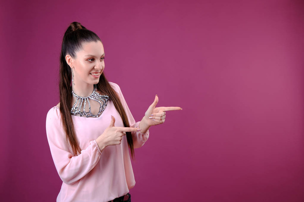 Smiling woman pointing finger side. portrait on pink background. - Photo, Image