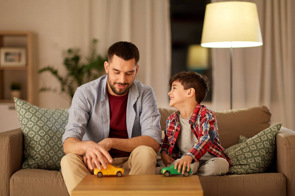 father and son playing with toy cars at home - Фото, зображення