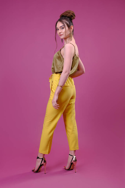 Portret van trendy jonge vrouw gekleed in gele broek - Foto, afbeelding