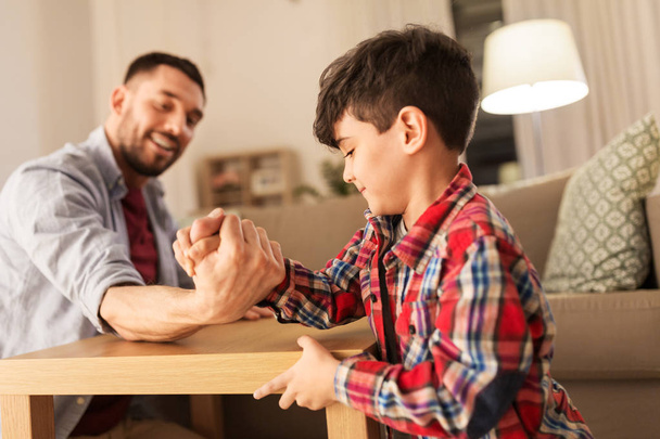 happy father and little son arm wrestling at home - Foto, Bild