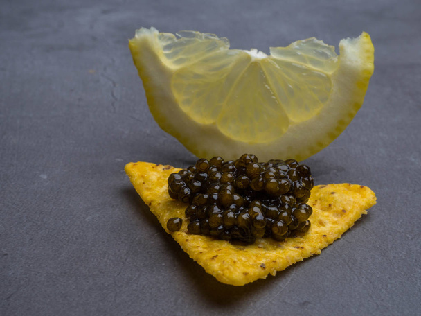 Zwarte kaviaar en citroen, gastronomisch eten, aperitief - Foto, afbeelding