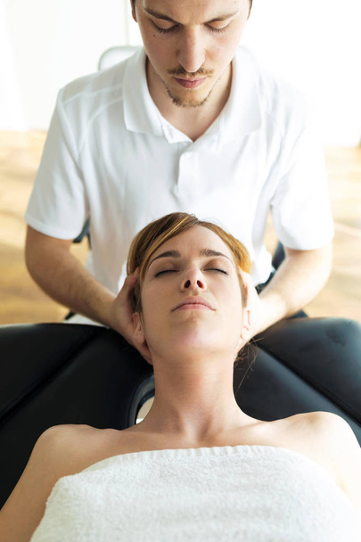 Jonge fysiotherapeut die de patiënt een nekbehandeling geeft in een fysiotherapieruimte.  - Foto, afbeelding