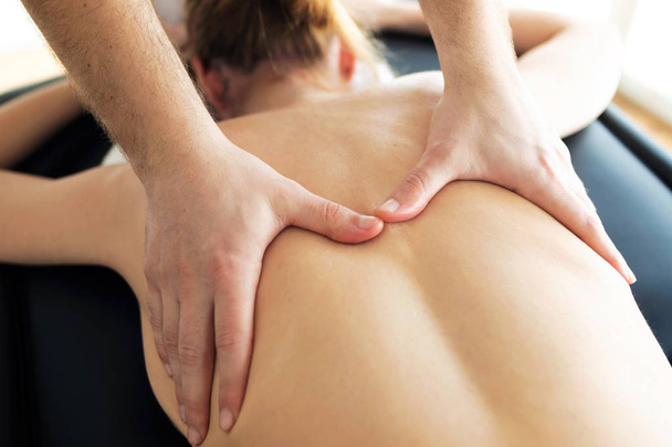 Young physiotherapist doing a back treatment to the patient in a physiotherapy room.  - Foto, imagen