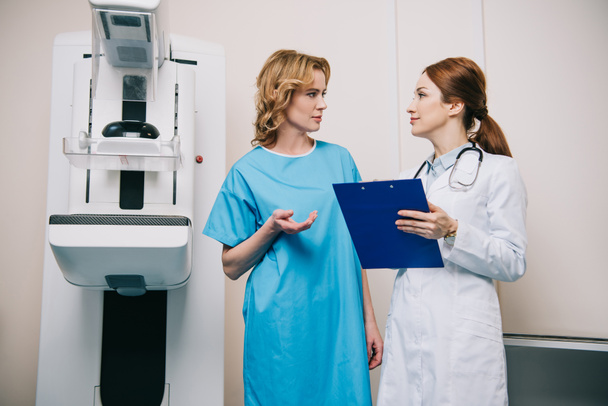 piękna kobieta rozmawia z radiologiem stojąc w pobliżu maszyny rentgenowskiej - Zdjęcie, obraz