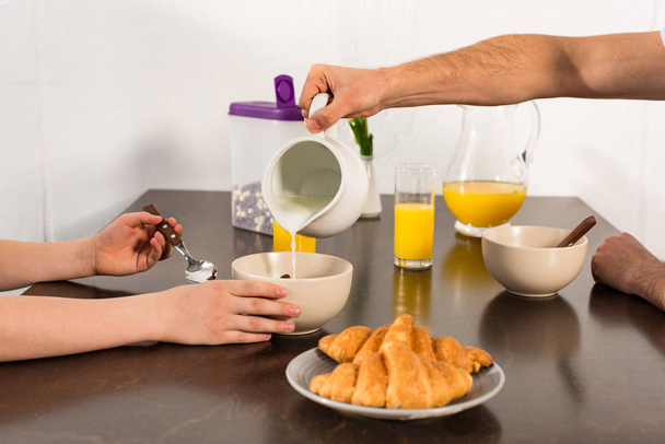 nyírt tekintettel az apa öntés tej tálba során reggeli fia - Fotó, kép