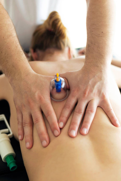 Physiotherapist applying cupping treatment to the patient in a physiotherapy room.  - Photo, Image