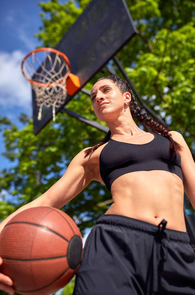 Mooie sexy fitness meisje in zwarte sport slijtage met perfect lichaam met basket bal op basketbalveld. Sport, fitness, lifestyle concept - Foto, afbeelding