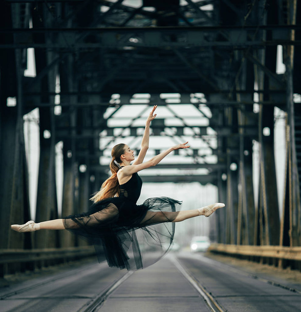 Балерина стрибає в шпагаті позі на дорозі і рейки. - Фото, зображення