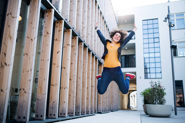 A young businesswoman jumping outdoors, expressing excitement. - Photo, Image