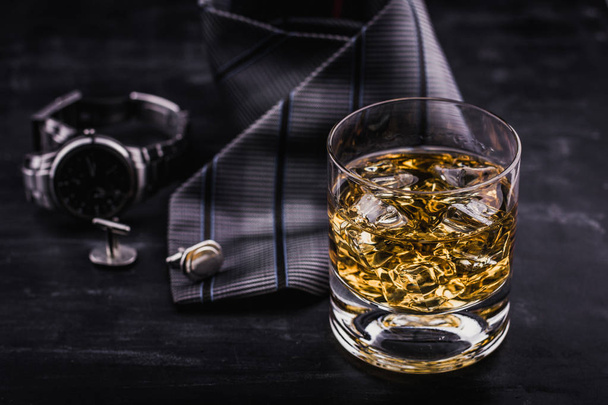 Concepto masculino para el día del padre. Corbata, relojes, gemelos y un vaso de whisky con hielo
 - Foto, Imagen