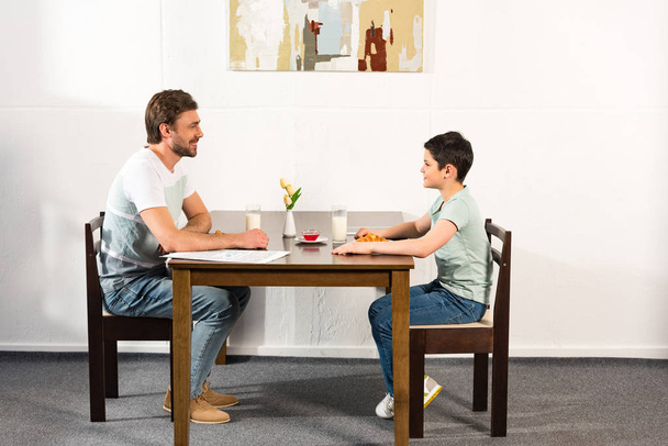 father and son looking at each other during breakfast in kitchen - Photo, image