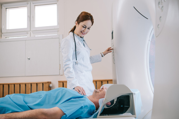 radiologista muito jovem preparando o homem para diagnósticos de tomografia em máquina de ressonância magnética
 - Foto, Imagem