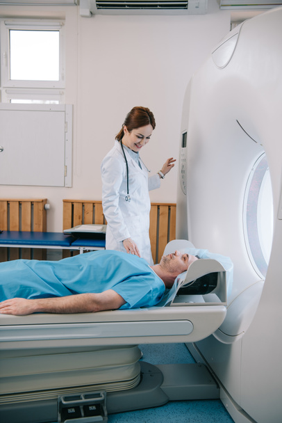 attractive smiling doctor preparing man for scanning in mri machine - Photo, Image