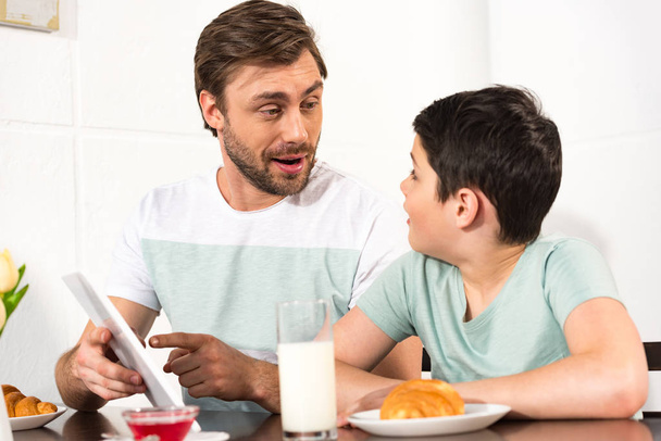 zaskoczony ojcem i synem przy użyciu cyfrowego tabletu podczas śniadania - Zdjęcie, obraz