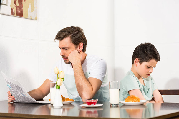 father reading newspaper and offended son during breakfast - Photo, Image