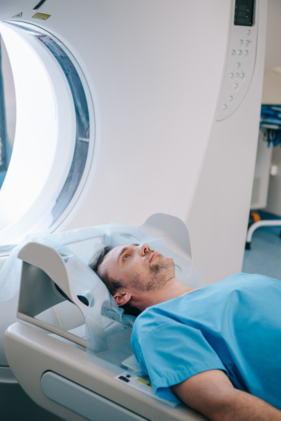 handsome man lying on ct scanner bed while having tomography test - Photo, Image