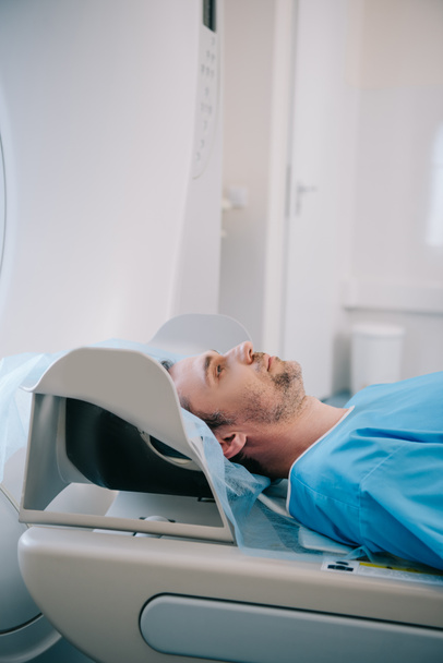 handsome man lying on ct scanner bed during tomography diagnostics in hospital - Fotó, kép