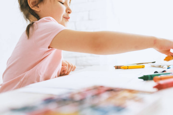 Little artist girl drawing with colorful pencils, wearing pink t-shirt. Cute preschooler child painting and learning at kindergarten. People, childhood, education - Foto, afbeelding