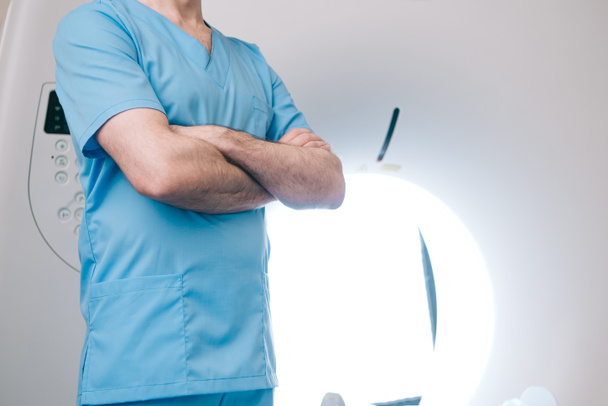 vista parziale del medico in piedi con braccia incrociate vicino allo scanner ct
  - Foto, immagini