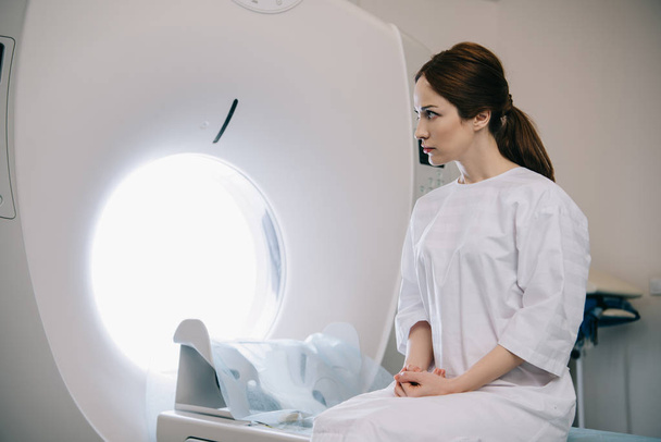 attractive woman sitting on computed tomography scanner bed in hospital - Foto, Bild