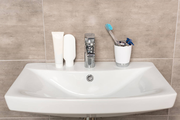 borotválkozó borotvák, fogkefe, fogkrém és sampon a mosdó a fürdőszobában - Fotó, kép