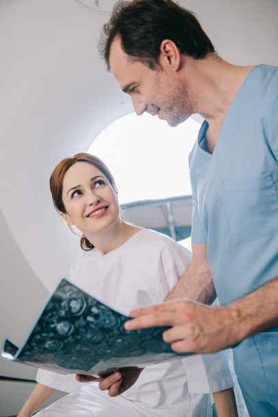sonriente médico mostrando tableta digital con diagnóstico de rayos X al paciente feliz
 - Foto, Imagen