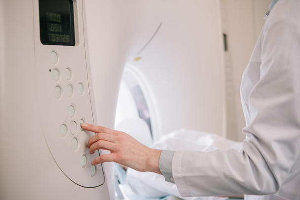 обрезанный вид рентгенолога, работающего на МРТ, пока пациент лежит на кровати МРТ
 - Фото, изображение