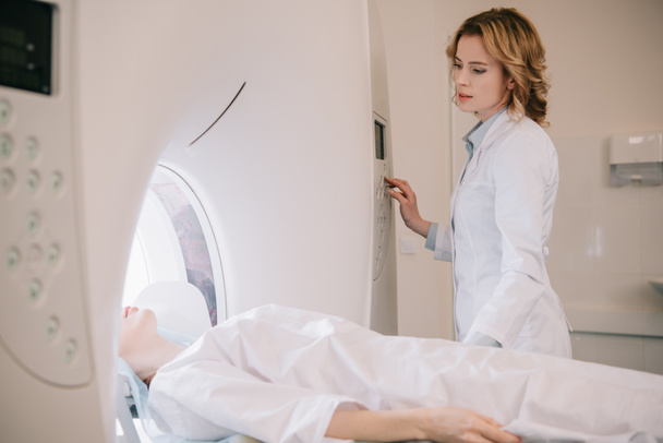 radiografía atenta que opera el escáner del ct durante diagnósticos de la tomografía de los pacientes
 - Foto, imagen