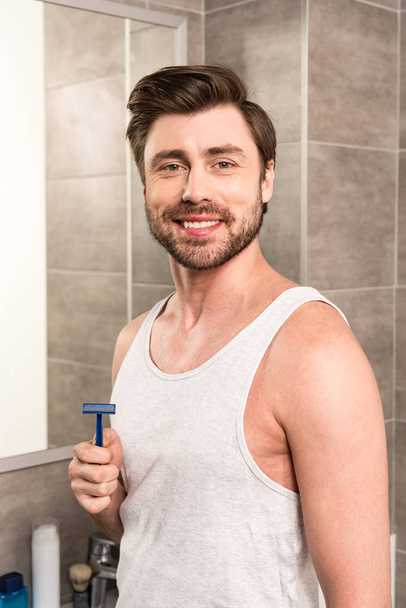 barbuto bell'uomo che tiene rasoio da barba in bagno
 - Foto, immagini