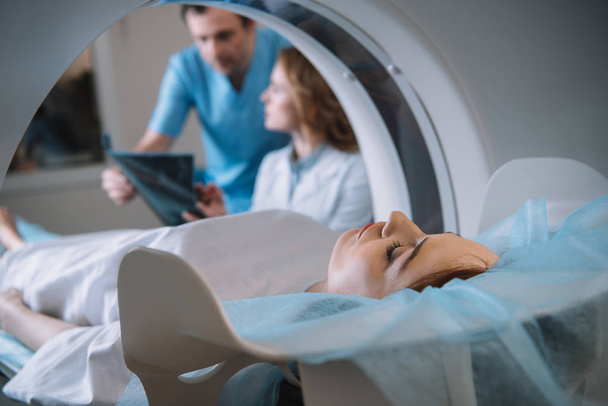 επιλεκτική εστίαση των στοχαστικό γιατρούς που εξετάζουν τη διάγνωση ακτίνων χ κατά τη διάρκεια των διαγνωστικών ασθενών σε CT σαρωτή - Φωτογραφία, εικόνα