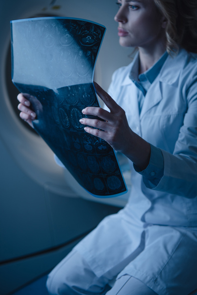 médecin réfléchi tenant diagnostic par rayons X tout en étant assis au scanner de tomodensitométrie
 - Photo, image