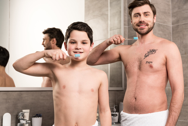smiling son and dad brushing teeth in bathroom - Foto, imagen