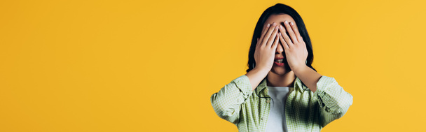 Casual brunette vrouw sluiten gezicht geïsoleerd op geel - Foto, afbeelding