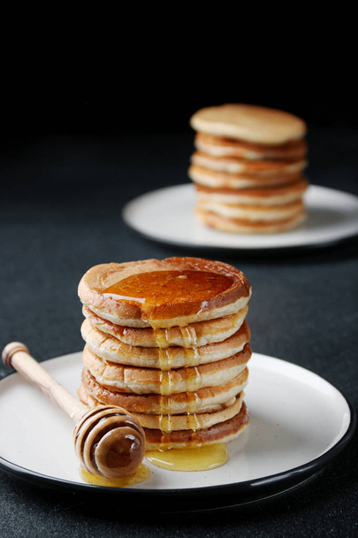 Stack of Pancakes with pouring honey on dark background. honey spoon - Φωτογραφία, εικόνα