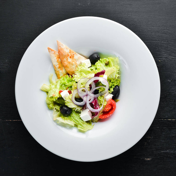 Greek salad. Vegetable salad with feta cheese, olives and cherry tomatoes. In the plate. Top view. Free space for your text. Rustic style. - Zdjęcie, obraz
