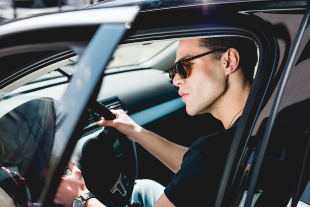selective focus of handsome stylish man in sunglasses driving car  - Photo, Image