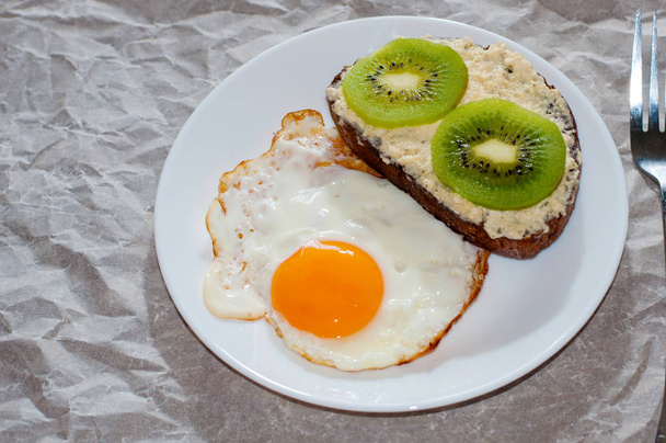 Colazione deliziosa e sana. Uova fritte e sandwich di kiwi su un piatto bianco, primo piano, spazio per il testo
 - Foto, immagini
