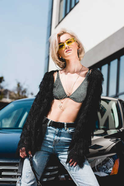 beautiful fashionable sexy young woman in glasses posing near car - Photo, image