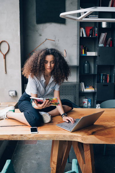 young curly woman sitting on table with laptop - Foto, Imagem