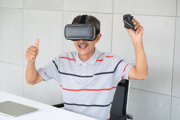 Öreg-ban VR valóság szemüveg-ból tényleges valóság-val gamepad játék, idősebb ember élvez és boldog-ban szünet. - Fotó, kép
