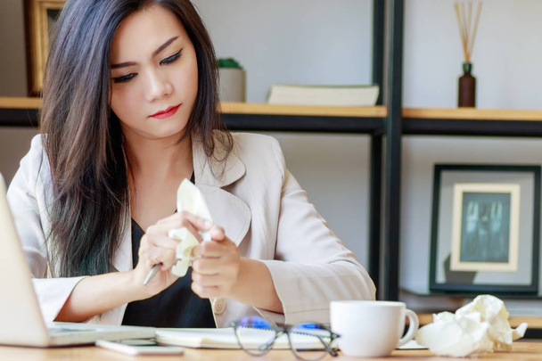Asian businesswoman squeeze paper in hand sitting at office desk covered with crumpled paper, feeling tired after work fail, give up, no idea - Foto, Bild