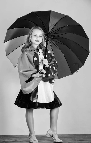 Waterproof accessories make rainy day cheerful and pleasant. Confident in her fall garments. Waterproof accessories manufacture. Kid girl happy hold colorful umbrella wear waterproof cloak - Photo, Image