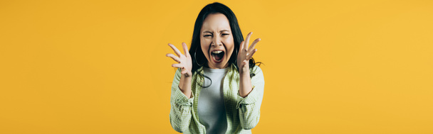 boze Aziatische vrouw gebaren en schreeuwen geïsoleerd op geel - Foto, afbeelding