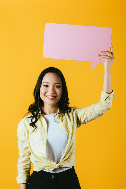 привлекательная азиатская женщина держит розовый пузырь речи, изолированный на желтый
 - Фото, изображение