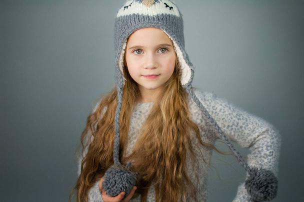 Gyönyörű mosolygó tizenéves lány, hosszú hajú, téli kalap-szürke-ezüst háttér - Fotó, kép