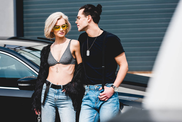 stylish handsome man and beautiful girl in bra posing near car - Photo, image